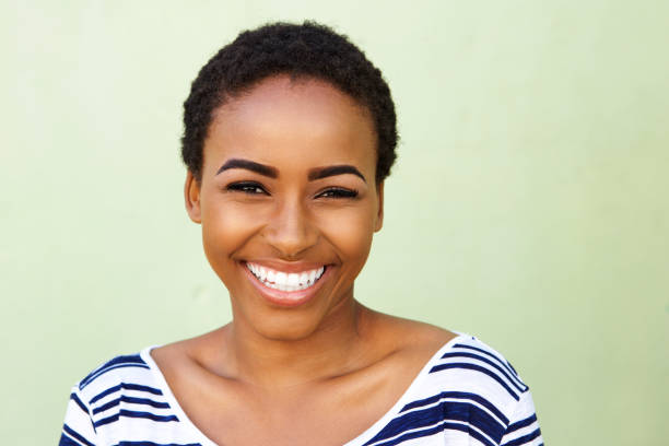 Close up portrait of young black woman smiling against green wall